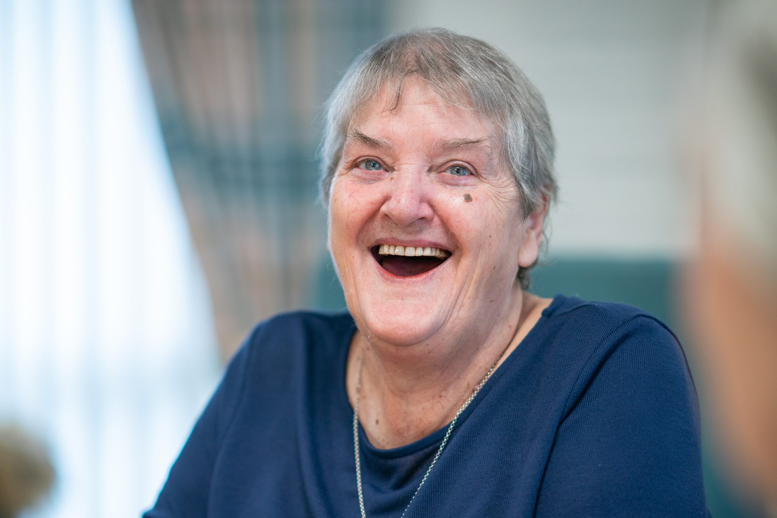 Joyful senior woman with a heartfelt laugh sharing a moment of happiness.