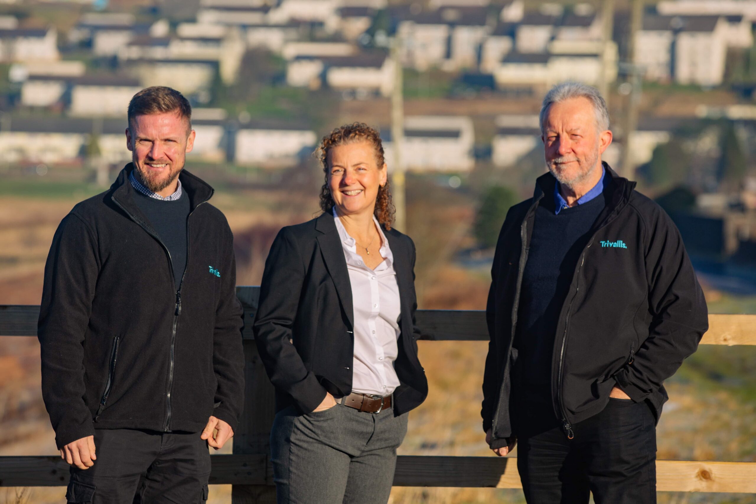 Trivallis Housing Landlord Wales Three professionals from Trivallis Community Housing standing outdoors with a smile, likely colleagues, with a blurred background of a residential area.