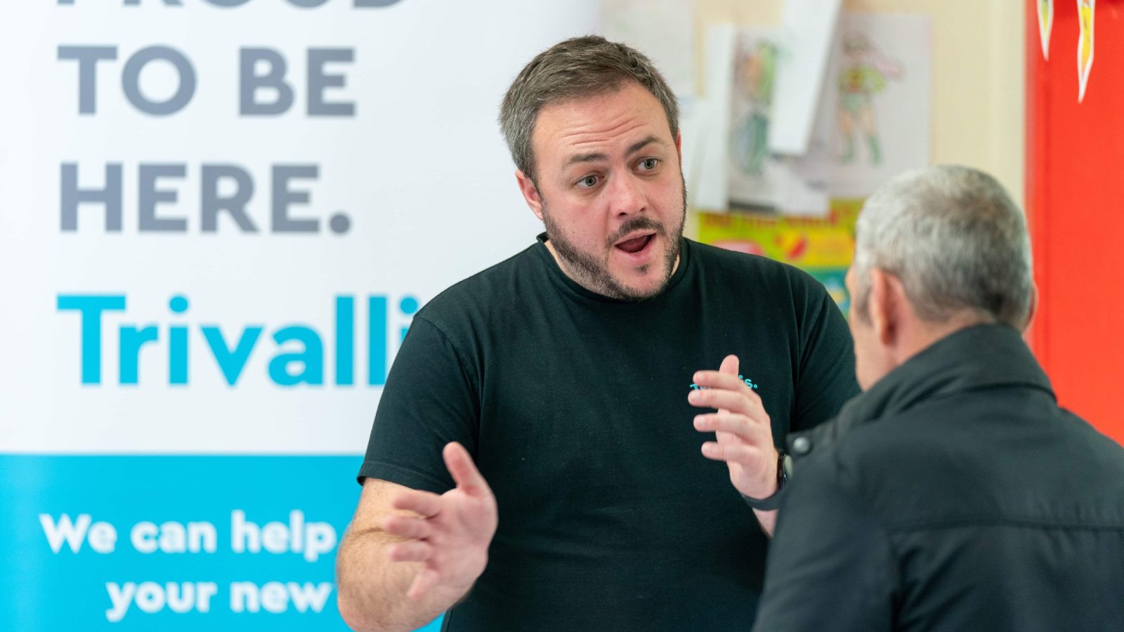 Trivallis Housing Landlord Wales A man gestures while speaking intensely to another person, with a banner reading 