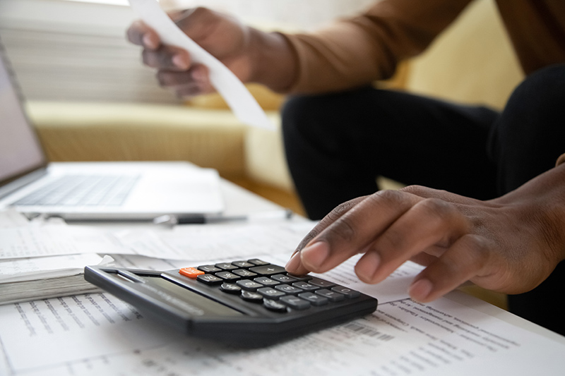 Trivallis Housing Landlord Wales A person using a calculator and reviewing documents, possibly managing finances or doing accounting work for Trivallis housing.