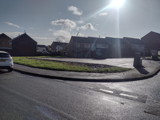 Trivallis Housing Landlord Wales A quiet residential neighbourhood on a sunny day with clear blue skies, featuring a cul-de-sac with houses and parked cars.