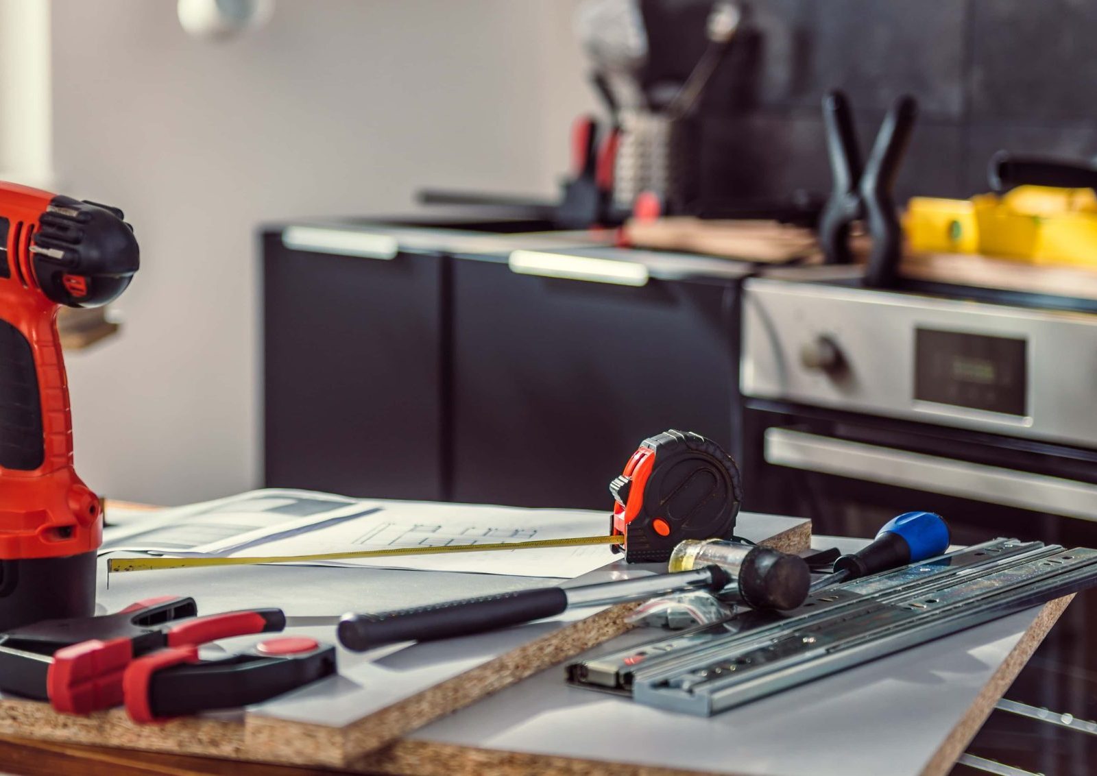 Trivallis Housing Landlord Wales A well-used work surface with various tools, including a cordless drill, tape measure, hammer, and pieces of hardware, suggesting an ongoing planned improvement project in Trivallis homes.