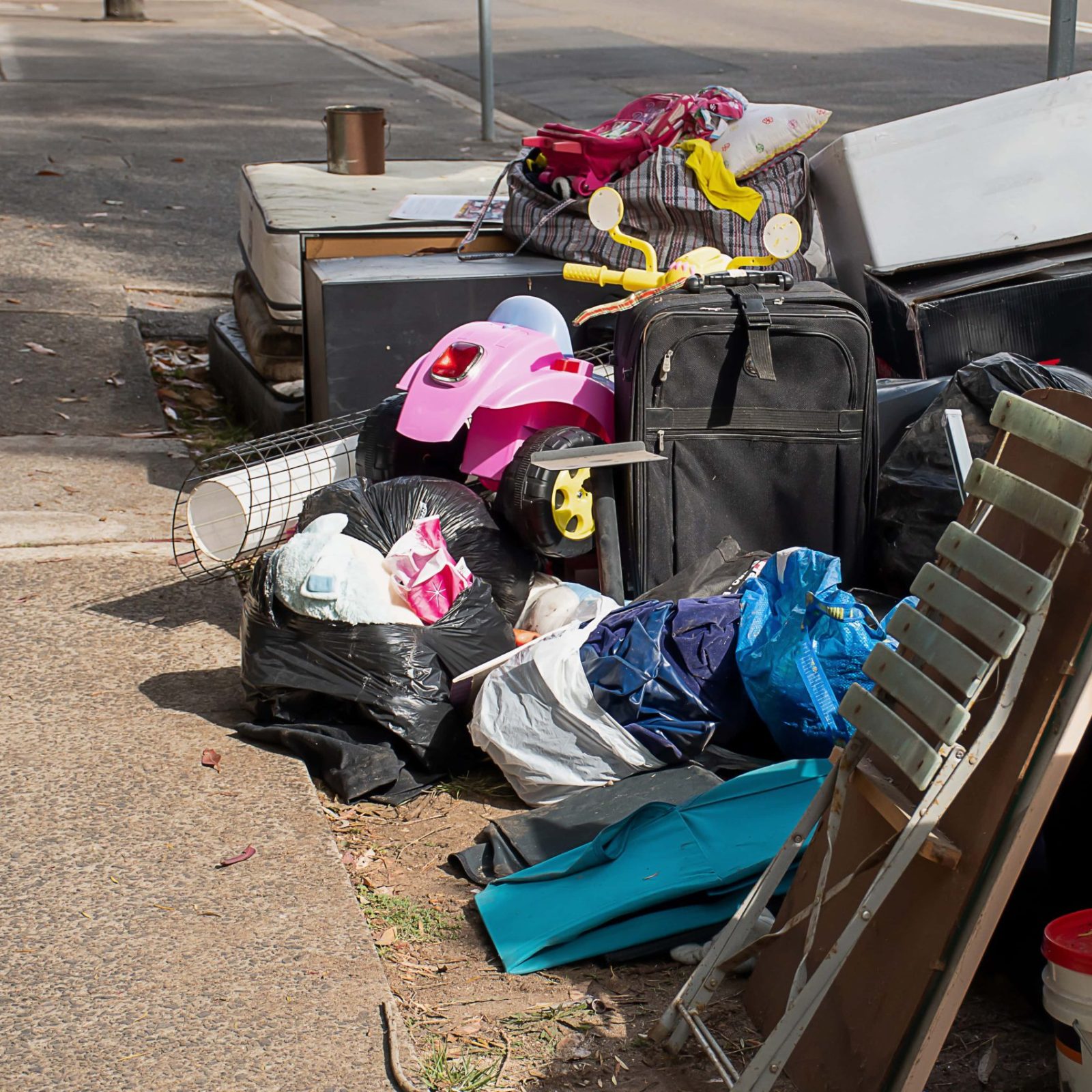 Trivallis Housing Landlord Wales A variety of discarded items, including luggage, furniture, and household goods, piled on a pavement for waste collection. Reporting a waste problem helps us keep things tidy.