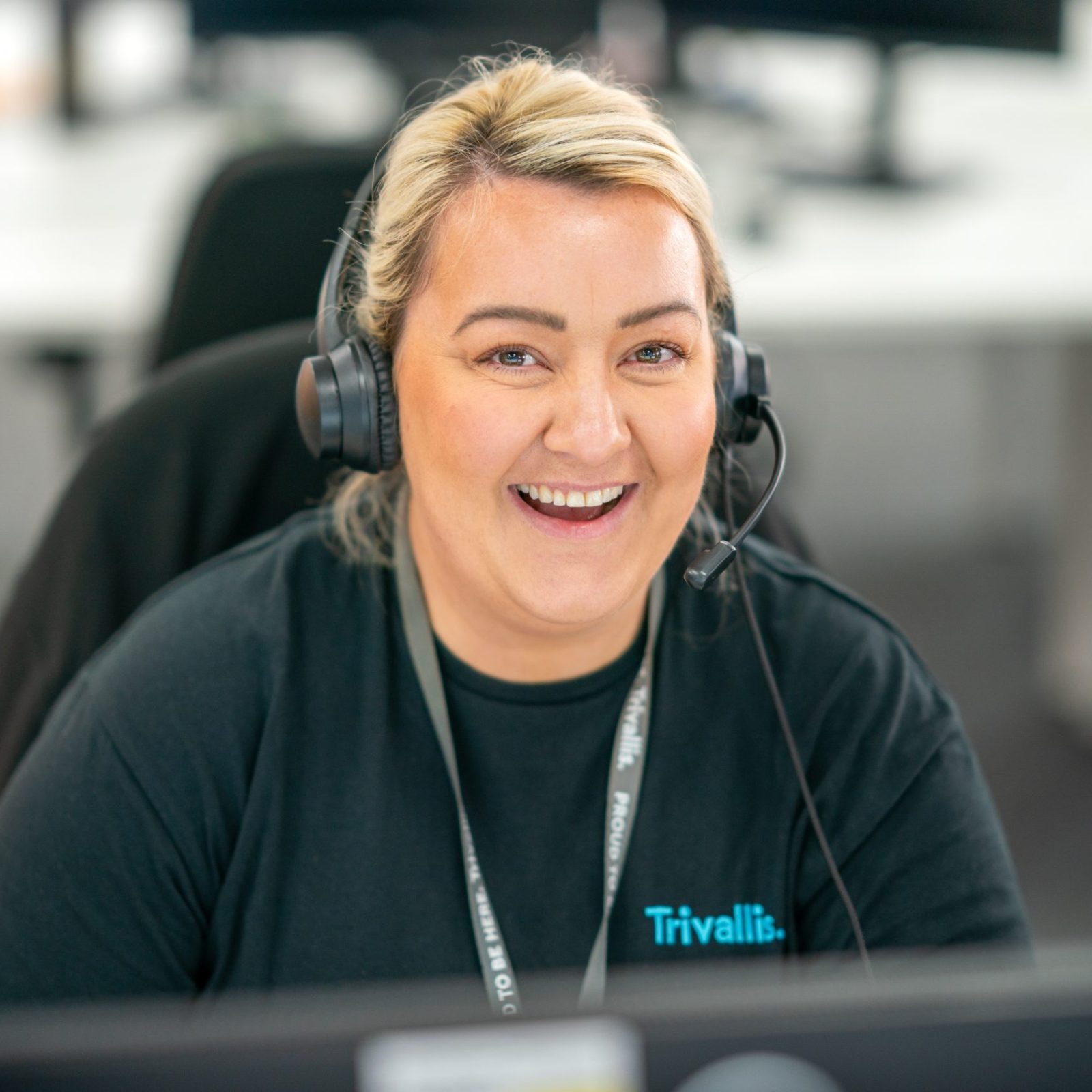 Trivallis Housing Landlord Wales A cheerful woman with blonde hair wearing a headset and a black shirt labelled 