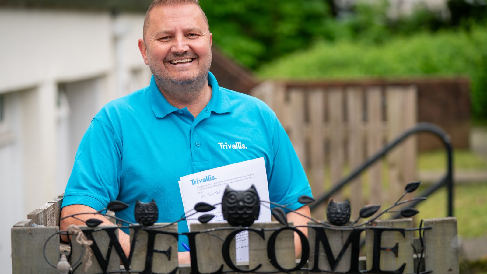 Trivallis Housing Landlord Wales A person in a blue shirt, holding a document, stands behind a decorative 